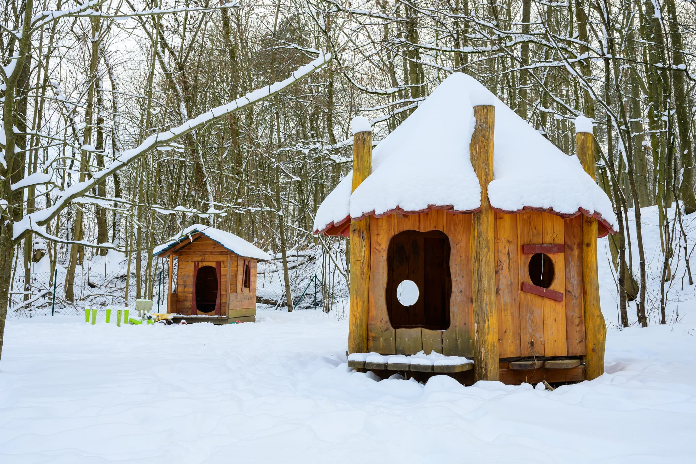Holzspielhäuser im verschneiten Wald – Winter am Waldkindergarten